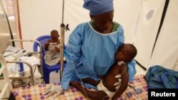 FILE - Ebola survivor Jeanine Masika Mbuka Furana Katungu holds Furana Katungu, a two-year-old confirmed ebola patient, inside the Biosecure Emergency Care Unit (CUBE) at ALIMA (The Alliance for International Medical Action) Ebola treatment center in Beni, DRC, March 31, 2019.