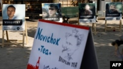 FILE - A poster showing Russian opposition leader Alexei Navalny (L) with the word "poisoned" and a mock offering of "Novichok Tea" are seen outside the Russian embassy in Berlin, Germany, during a protest, Sept. 23, 2020.
