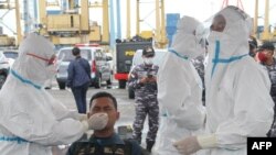 Health workers test a rescue worker for the Covid-19 coronavirus at the port in Jakarta on January 10, 2021, as part of the ongoing search operation for Sriwijaya Air flight SJY182 which crashed after takeoff from Jakarta on January 9. (Photo by Dany Kris