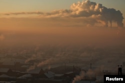 Power plant chimneys stand behind a coal burning neighborhood covered in a thick haze on the outskirts of Ulaanbaatar, Mongolia, Jan. 19, 2017.