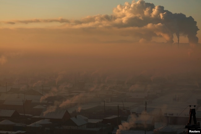 FILE - Power plant chimneys stand behind a coal-burning neighborhood covered in a thick haze on the outskirts of Ulaanbaatar, Mongolia, Jan. 19, 2017.