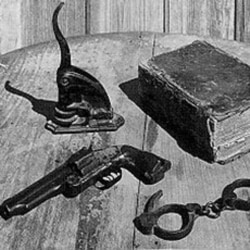 The tools of Texas lawman Judge Roy Bean: a notary seal, a book of law, handcuffs and a gun