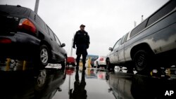 FILE - An Immigration and Customs Enforcement agent watches cars as they wait to enter the United States from Tijuana, Mexico, through the San Ysidro port of entry in San Diego, Dec. 3, 2014..