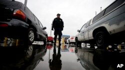 FILE - An Immigration and Customs Enforcement agent watches cars as they wait to enter the United States from Tijuana, Mexico, through the San Ysidro port of entry in San Diego, Dec. 3, 2014.