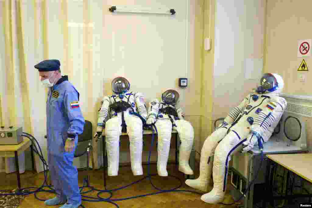 An employee stands near the space suits of U.S. astronaut Michael Hopkins, Russian cosmonauts Oleg Kotov and Sergey Ryazanskiy at the Baikonur cosmodrome, Kazakhstan. Hopkins, Kotov and Ryazanskiy are scheduled to be part of a mission to the &nbsp;International Space Station that will launch on Sept. 26, according to the Russian Federal Space Agency Roscosmos.