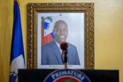 FILE - A picture of the late Haitian President Jovenel Moise hangs on a wall before a news conference by interim Prime Minister Claude Joseph, in Port-au-Prince, Haiti, July 13, 2021.
