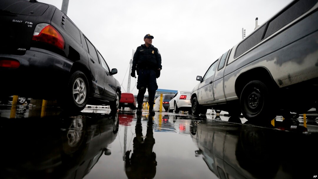 FILE - An Immigration and Customs Enforcement agent watches cars as they wait to enter the United States from Tijuana, Mexico, through the San Ysidro port of entry in San Diego, Dec. 3, 2014.