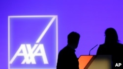 FILE - In this Feb. 21, 2019 photo, people stand in front of the logo of AXA Group prior to the company's 2018 annual results presentation, in Paris. 