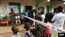 Les gens attendent en file à l'extérieur d'un bureau de vote lors des élections générales du pays à Freetown le 7 mars 2018.