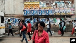 Pedestrians pass a wall with election posters in Antananarivo, Madagascar, Nov. 6, 2018 on the eve of elections in the Indian Island nation. 