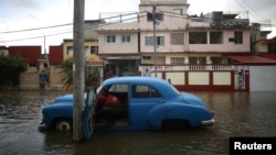 A man tries to start the engine of a vintage car in a flooded street in Havana, Cuba, January 23, 2017. 