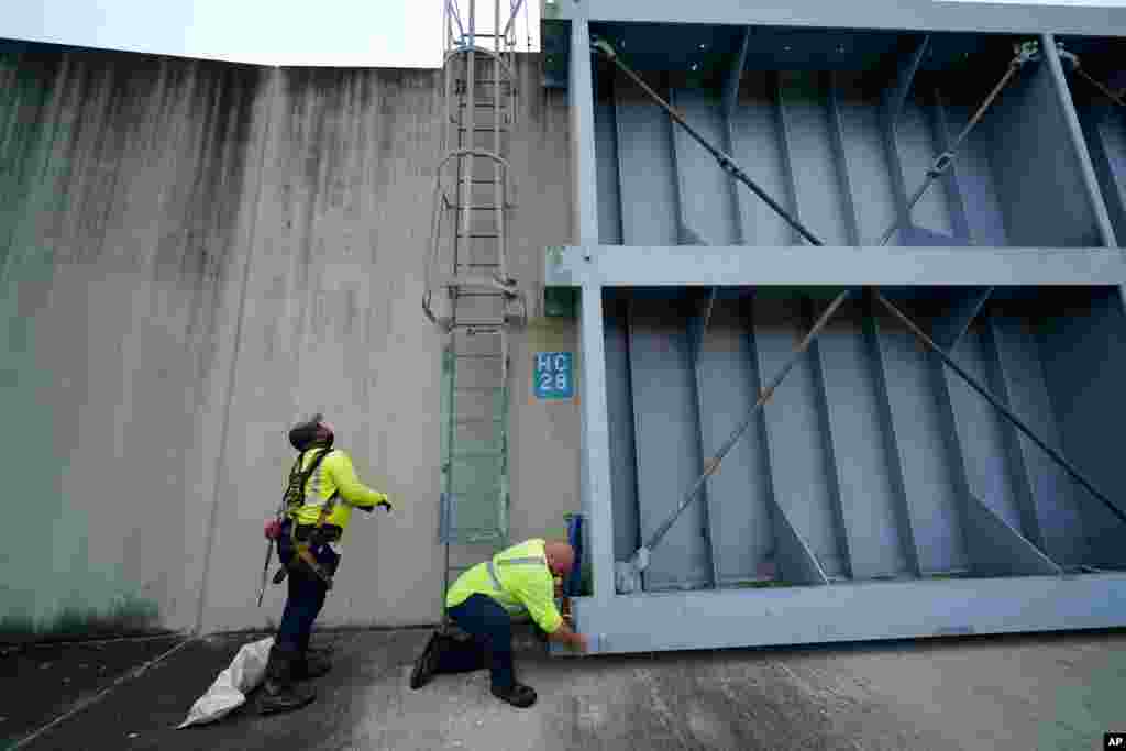 Workers for the Southeast Louisiana Flood Protection Authority - West close floodgates in Harvey, La., just outside New Orleans, Aug. 24, 2020.