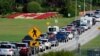 Una fila de vehículos espera para ingresar a Canadá en el cruce fronterizo de Peace Arch, a la vista de una bandera canadiense hecha de flores, el 9 de agosto de 2021, en Blaine, EE. UU.