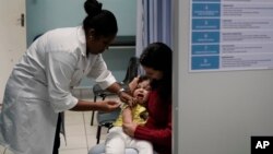 FILE - A health worker vaccinates a toddler against measles in Rio de Janeiro, Brazil, Aug. 6, 2018