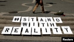 FILE - A sign used by a small group of demonstrators rests on steps during a demonstration to support intelligence contractor, Reality Winner, after she was charged with leaking classified documents, June 7, 2017.