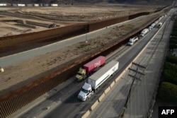 Truk-truk yang mengantre di samping tembok perbatasan sebelum menyeberang ke Amerika Serikat di pelabuhan komersial Otay di Tijuana, negara bagian Baja California, Meksiko, 22 Januari 2025. (Foto: AFP)