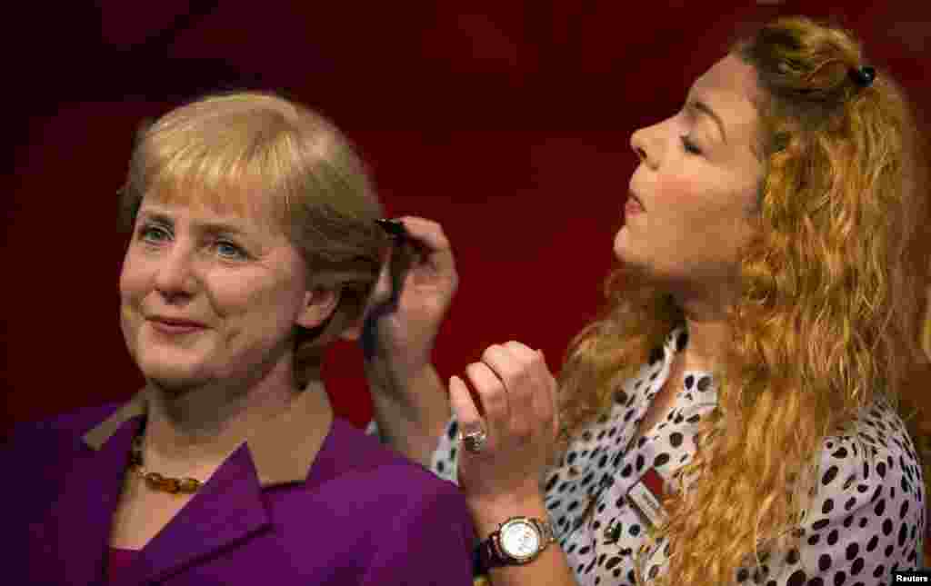 Nhân viên viện bảo tàng sáp Madame Tussauds ở Berlin đang chăm sóc mái tóc của Thủ tướng Đức Angela Merkel.