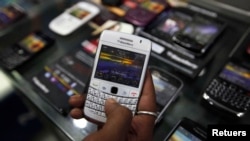 A customer holds a BlackBerry handset inside a mobile selling shop in Kolkata August 12, 2010. REUTERS/Rupak De Chowdhuri