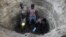 In this photo taken March 22, 2019, Kenyan children dig deep into a dry river bed to retrieve water in Tarach, Turkana county, in northern Kenya.