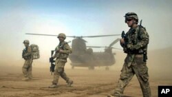 U.S. soldiers participating in the NATO- led International Security Assistance Force (ISAF) walk ahead of a Chinook helicopter near the place where the foundation of a hospital was laid in Shindand, Herat, west of Kabul, Afghanistan, January 28, 2012