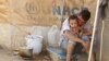 A Syrian refugee holds his child as he sits by his tent at Al Zaatri refugee camp in the Jordanian city of Mafraq, near the border with Syria, September 9, 2012. 