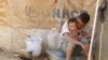 A Syrian refugee holds his child as he sits by his tent at Al Zaatri refugee camp in the Jordanian city of Mafraq, near the border with Syria September 9, 2012. 