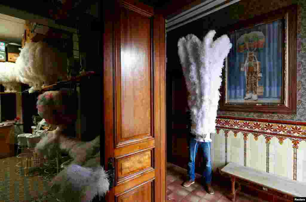 An artisan poses with an ostrich feather-adorned hat worn by the "Gilles of Binche" performers during the Binche carnival, a UNESCO World Heritage event, in a shop in Binche, Belgium, Feb. 1, 2019.