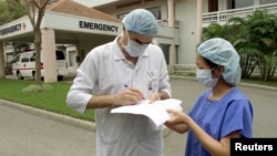 Lucien Blanchard, general manager of the Vietnam-France Hospital, signs a form for a nurse outside the facility in capital city Hanoi, March 2003.