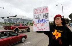 FILE - Native American Steve Morales, of Dallas, holds up a sign as he joins others in protest outside of an NFL football game between the Washington Redskins and Dallas Cowboys in Arlington, Texas, Oct. 13, 2013.