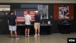 在纽约9/11国家纪念博物馆内，参观者站在一面展出的美国国旗前。