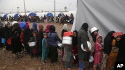 Displaced Iraqis, who fled fighting between Iraqi security forces and Islamic State militants, gather for food at a camp for internally displaced people in Hamam al-Alil, some 10 kilometers south of Mosul, Iraq, March 2, 2017.