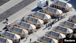 FILE - Immigrant children housed in a tent encampment under the zero tolerance policy by the Trump administration are shown walking in single file at the facility near the Mexican border in Tornillo, Texas, June 19, 2018.