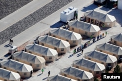 Immigrant children housed in a tent encampment under the "zero tolerance" policy by the Trump administration are shown walking in single file at the facility near the Mexican border in Tornillo, Texas, June 19, 2018.