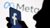 Arhiva - Žena drži smartfon sa logoom Facebooka na ekranu, ispred novog logoa kompanije Meta, na ilustraciji od 28. oktobra 2021.