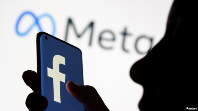 A woman holds a smartphone with the Facebook logo in front of a display of Facebook's new rebrand logo Meta in this illustration picture taken Oct. 28, 2021.