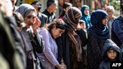 FILE - Iraqi Yazidi women and children rescued from the Islamic State group wait to board buses bound for Sinjar in Iraq's Yazidi heartland, April 13, 2019.