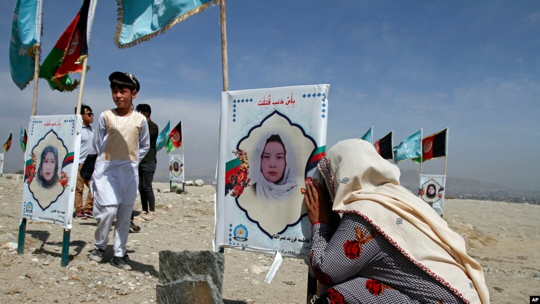 An Afghan woman cries next to the grave of her daughter, adorned with her picture, on the outskirts of Kabul, Afghanistan, Sept 14, 2020. 