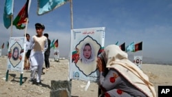 An Afghan woman cries next to the grave of her daughter, adorned with her picture, on the outskirts of Kabul, Afghanistan, Sept 14, 2020. 
