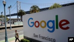  man walks past a Google sign outside with a span of the Bay Bridge at rear in San Francisco, May 1, 2019.