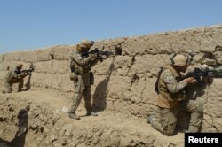 FILE - Afghan security forces take position during a battle with the Taliban in Kunduz province, Afghanistan, Sept. 1, 2019.
