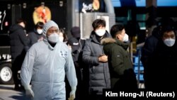 FILE: A South Korean soldier wearing a protective suit walks past people who wait in a line to undergo a coronavirus disease (COVID-19) test at a coronavirus testing site