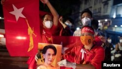 Seorang pendukung Liga Nasional untuk Demokrasi memegang foto Penasihat Negara Myanmar Aung San Suu Kyi saat menunggu hasil di luar markas partai usai pemilihan umum di Yangon, Myanmar, 8 November 2020. (Foto: REUTERS/Shwe Paw Mya Tin )