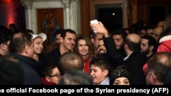 Syrian President Bashar al-Assad, center left, and his wife, Asma al-Assad, center right, pose for a picture with a Syrian man at a Christmas choral presentation at the Lady of Damascus Catholic Church, in Damascus, Dec. 18, 2015. 