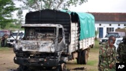 'Yan sanda tsaye kusa da wata motar da aka kona lokacin da 'yan bindiga suka kai farmaki yau lahadi a kofar caji ofis na Gamba a kasar Kenya