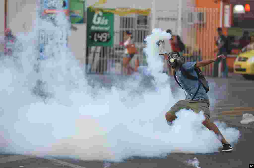 Um manifestante prepara-se para atirar uma bomba de gás contra a polícia, fora da Estação Central de comboios, durante o protesto contra o aumento das tarifas de autocarro no Rio de Janeiro, Fev. 6, 2014.