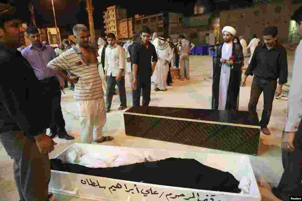 Mourners stand beside coffins of four members of a family killed in Basra bomb attacks, during a funeral in Najaf, Iraq, May 20, 2013. 