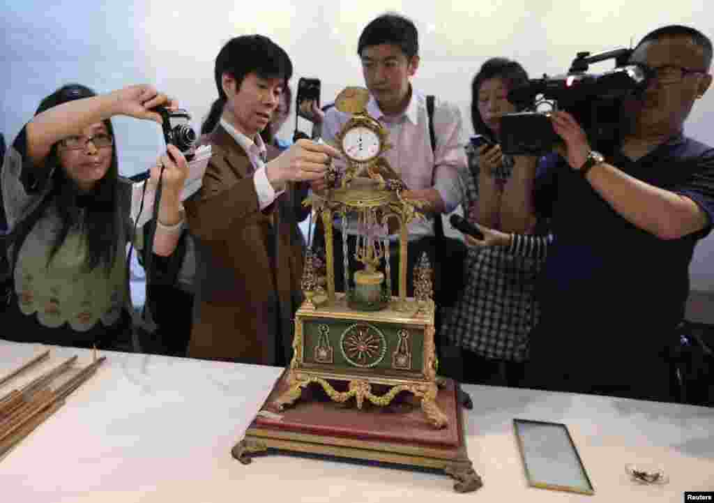 Guo Fuxiang (2nd L), a researcher of the Palace Museum, introduces the damaged Qing Dynasty clock to journalists during a media briefing at the Forbidden City in Beijing, China. A man broke a window with his bare hands while touring the museum, knocking the clock onto the ground and causing the damage.