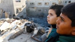 Filistinli çocuklar, Gazze Şeridi'nin güneyindeki Han Yunus'ta, İsrail'in evlere düzenlediği saldırıların enkazına bakıyor. (10 Aralık 2023)