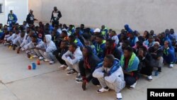 FILE - Migrants wait before being deported by Libyan authorities, in Misrata, Libya, Feb. 19, 2018.