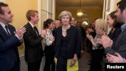 Le personnel applaudit le nouveau Premier ministre britannique Theresa May, et son mari Philip, qui viennent de rencontrer la reine Elizabeth à Buckingham Palace, à Londres, la Grande-Bretagne, 13 juillet 2016. REUTERS / Stefan Rousseau 